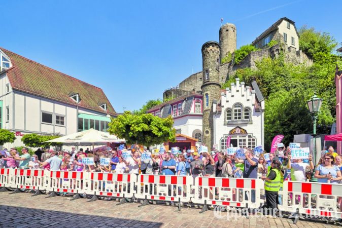 Mit hochgereckten Eppstein-Schildern grüßen die Zuschauer den Radrenn-Tross vor der Alt­stadtkulisse.Foto: Walter Adler/adler-photoart.de