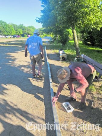 Fast wie in Südfrankreich: Helfer mit Sonnenhut auf dem Kopf befestigen die neue Umrandung am Boule-Platz in Bremthal.Foto: privat