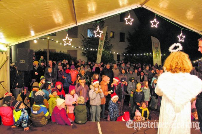 Engel Emily (r.) liest eine Weihnachtsgeschichte vor, Kinder und Erwachsene in der festlich geschmückten Wooganlage lauschen aufmerksam.Foto: Julia Palmert